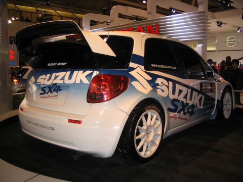 1993 Ford Taurus - A Suzuki SX4 rally car with 'Rally Concept' branding is displayed at an auto show.