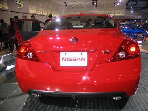 1993 Ford Taurus - A red Nissan Altima sedan is displayed at an auto show, with another blue car visible in the background.