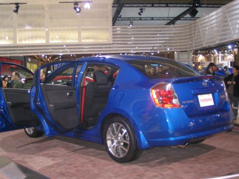 1993 Ford Taurus - A blue Nissan Sentra is displayed with its doors open at an auto show.
