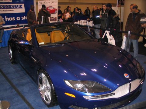 1993 Ford Taurus - A blue convertible sports car is displayed indoors with people in the background.