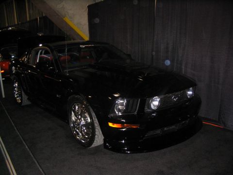 1993 Ford Taurus - A black Ford Mustang is displayed indoors with its hood open, showing red interior details.