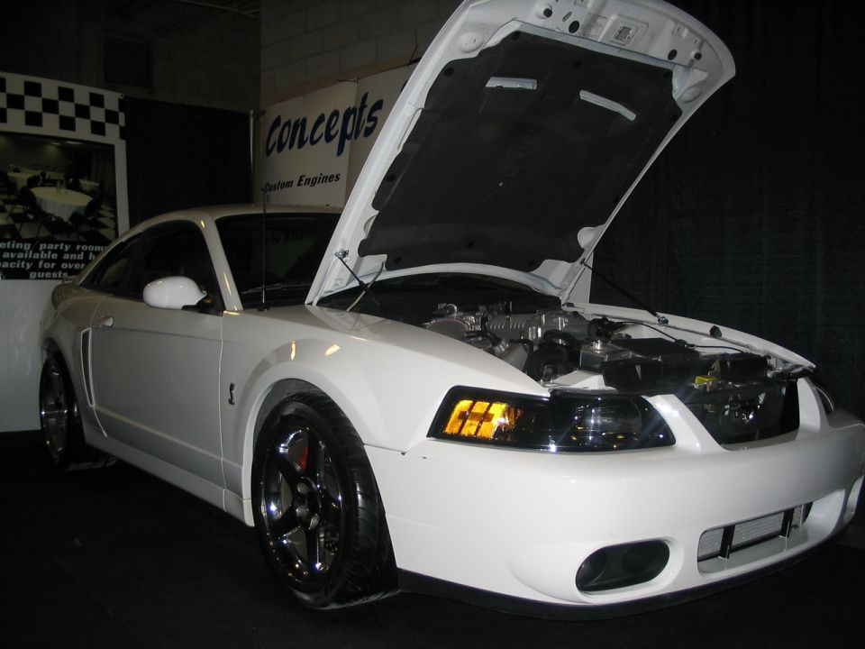 White Ford Mustang with hood open, showing engine. Front 3/4 view