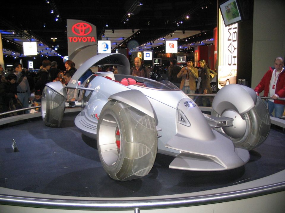 Futuristic concept car with large wheels and open cockpit on display