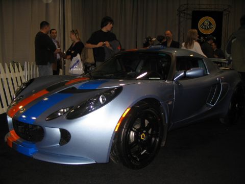 1993 Ford Taurus - A Lotus Elise is displayed at an auto show with people in the background.