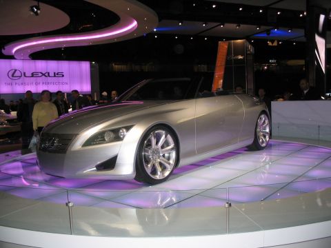1993 Ford Taurus - A silver convertible concept car is displayed under purple lighting at an auto show, with Lexus branding visible.