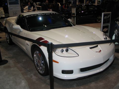 1993 Ford Taurus - A white Corvette with racing stripes is displayed at an auto show.