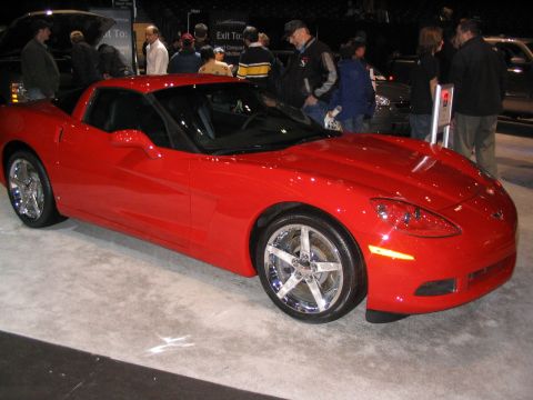 1993 Ford Taurus - A red sports car is displayed indoors, likely at an auto show, with people in the background.