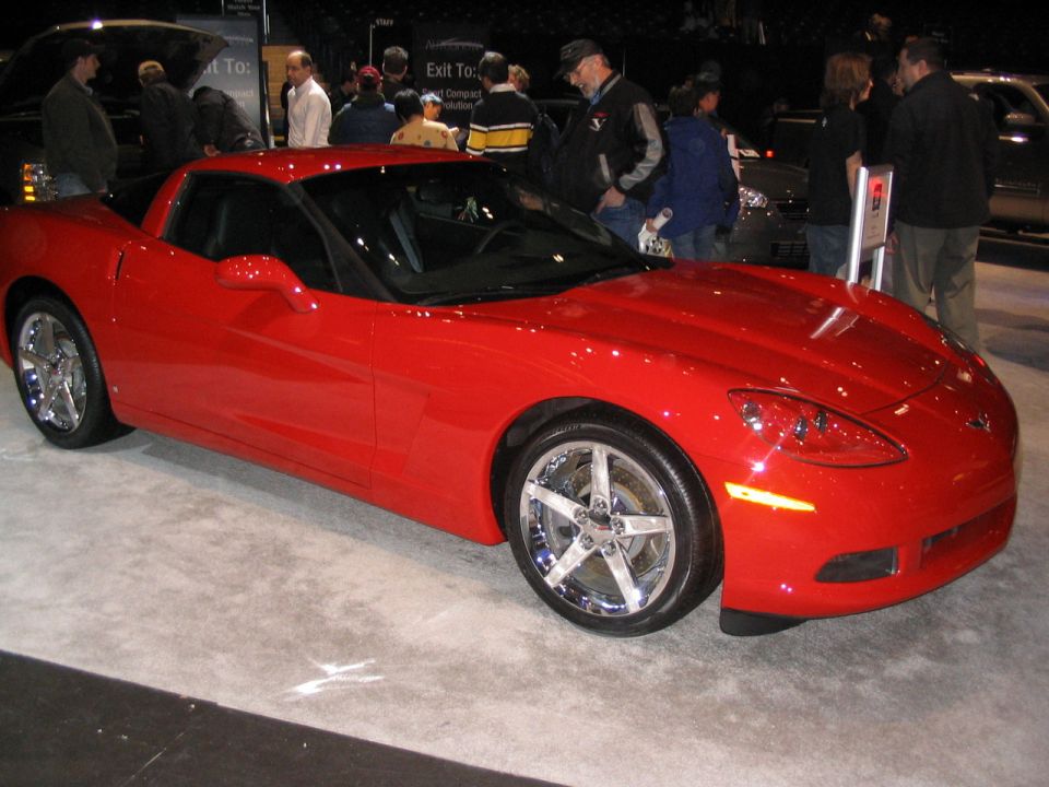Red sports car with chrome five-spoke wheels, seen from a 3/4 front angle