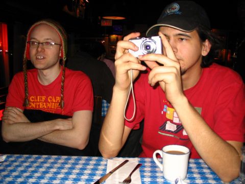 1993 Ford Taurus - Two men are seated at a table with a blue and white checkered tablecloth. One is taking a photo.