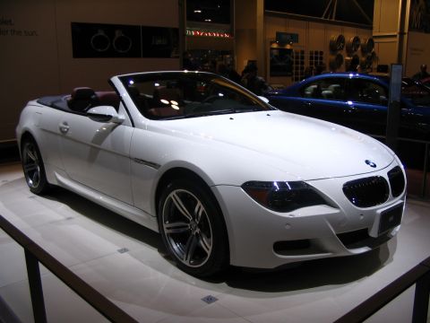 1993 Ford Taurus - A white convertible is displayed at an auto show with a blue car in the background.
