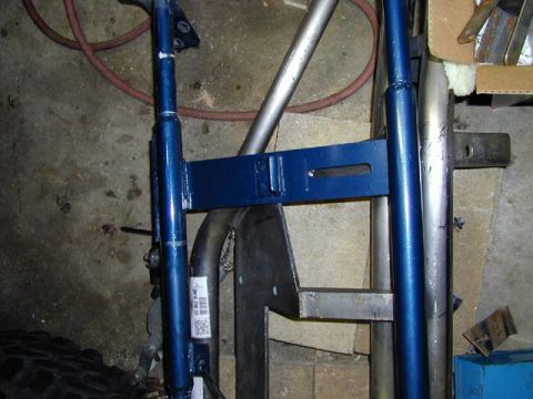 1979 Ford Bronco - Close-up of blue painted suspension components and a tire in a workshop setting.