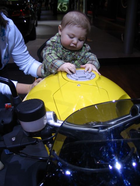 1993 Ford Taurus - A baby sits on the gas tank of a yellow motorcycle.