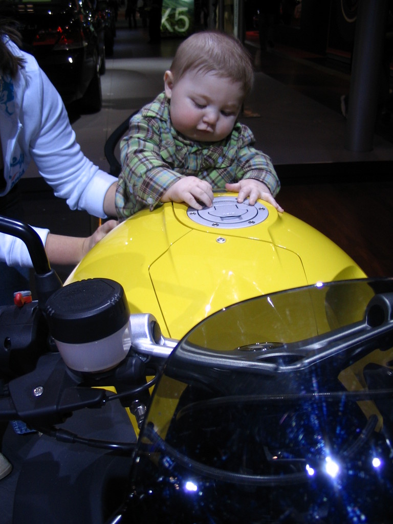 Baby on yellow motorcycle gas tank