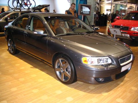 1993 Ford Taurus - Dark grey Volvo sedan with bikes on roof rack, seen at an auto show with a red SUV in the background.