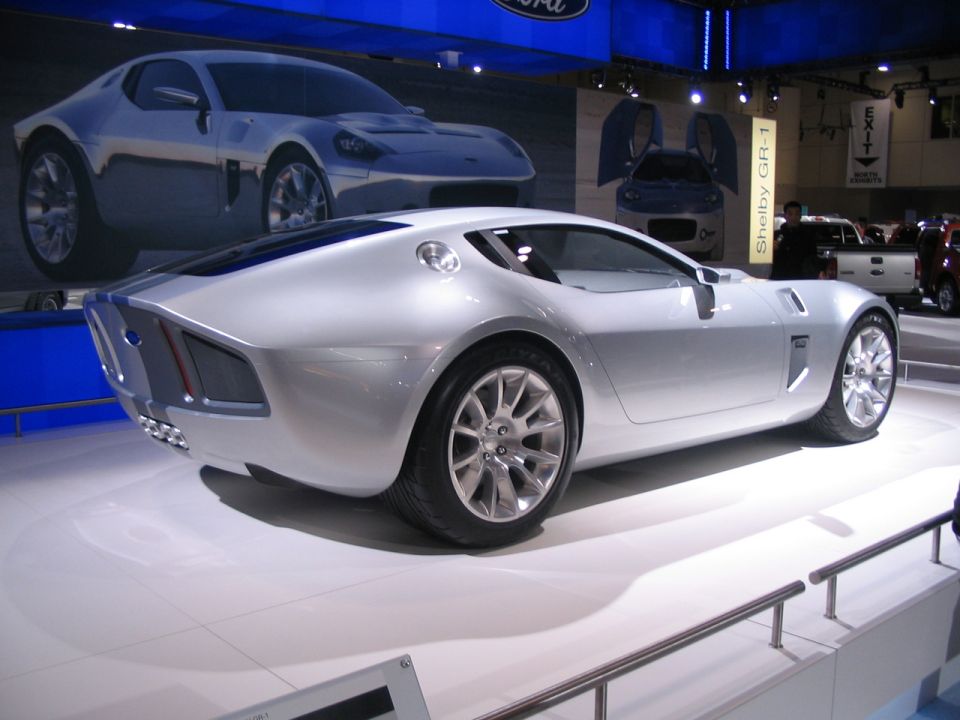 Silver Shelby GR-1 concept car on display, with a Ford logo and another car in the background