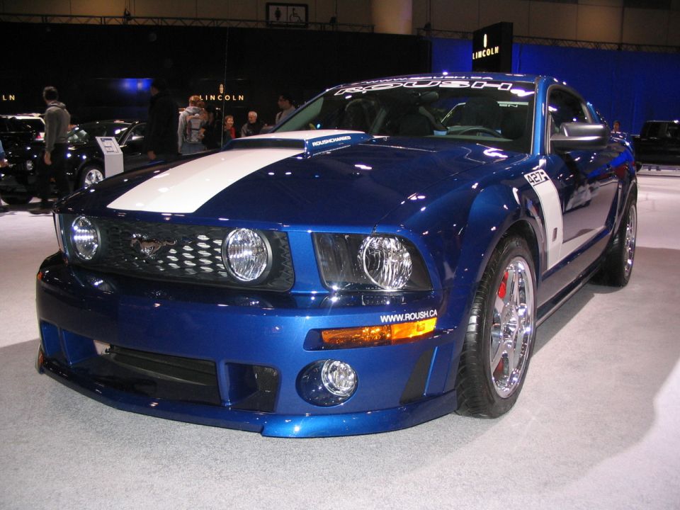 Blue Ford Mustang with white racing stripes and "ROUSH" badging