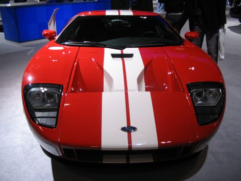 1993 Ford Taurus - A red Ford GT with white stripes is displayed at an auto show.