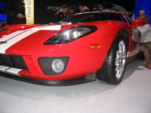 1993 Ford Taurus - A red Ford GT sports car with white stripes is displayed at an auto show.