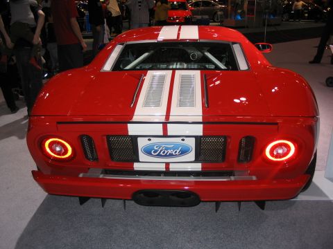 1993 Ford Taurus - Rear view of a red Ford GT sports car with white stripes, displayed at an auto show.