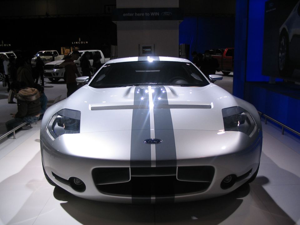 White Ford GT with grey racing stripes, front view, at an auto show