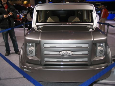 1993 Ford Taurus - A silver Ford concept van is displayed at an auto show, with people in the background.
