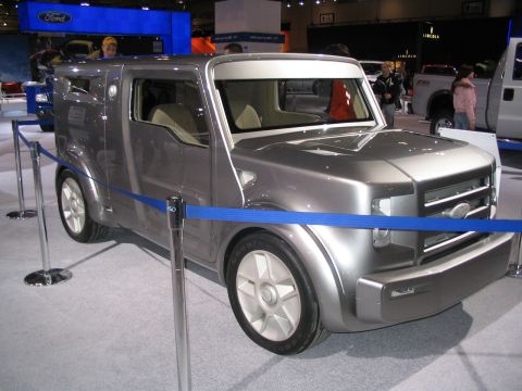 1993 Ford Taurus - A unique silver concept van with a distinctive boxy design is showcased at an auto show.