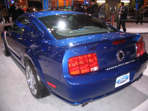 1993 Ford Taurus - A blue Ford Mustang is displayed at an auto show, a Roush.ca decal and a Ford license plate frame.