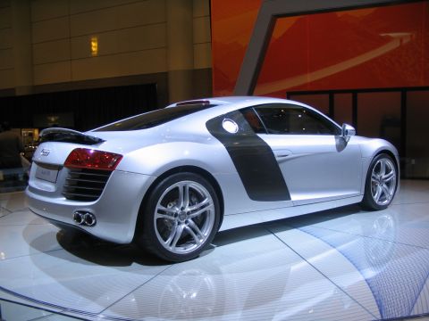 1993 Ford Taurus - A silver Audi R8 is displayed indoors on a reflective floor with a large orange graphic in the background.