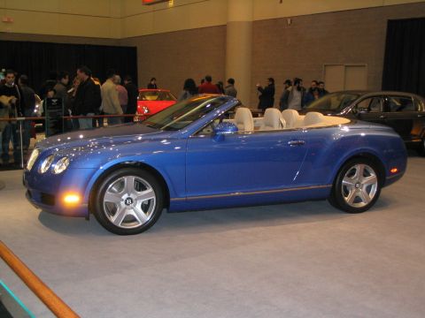 1993 Ford Taurus - A blue convertible is displayed at an auto show with people in the background.
