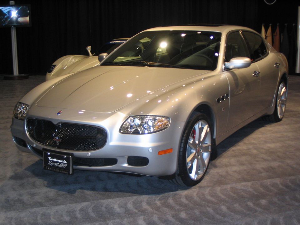 Silver Maserati Quattroporte on display, another car behind it