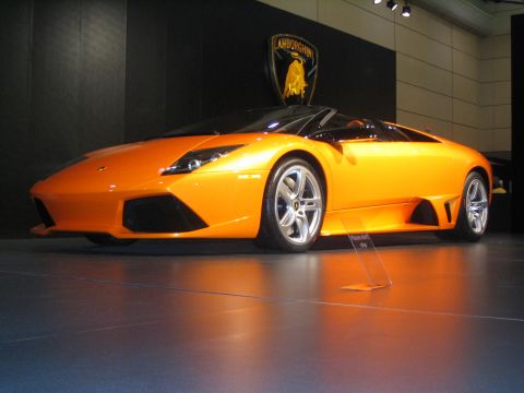 1993 Ford Taurus - An orange Lamborghini convertible is displayed indoors with the brand's shield logo visible in the background.