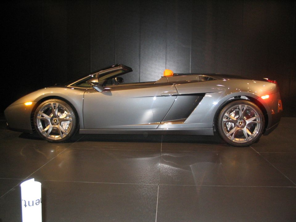 Silver convertible Lamborghini Gallardo Spyder with orange interior accents, side view