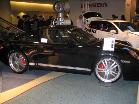 1993 Ford Taurus - A black Porsche 911 is displayed at an auto show, with a white Honda visible behind it.