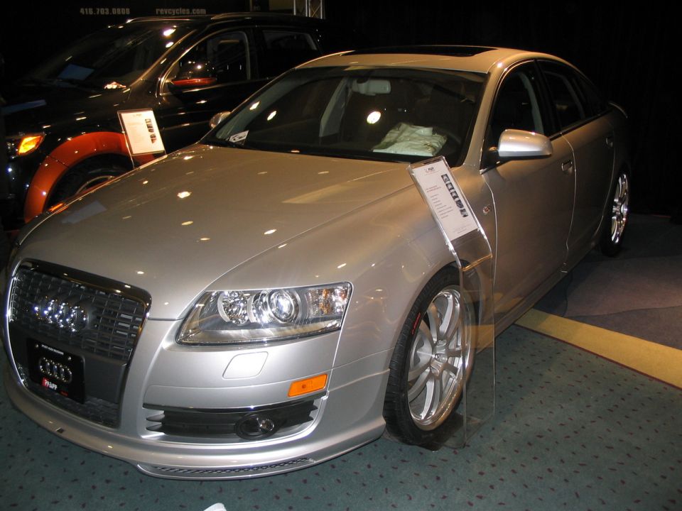 Silver sedan with a large grille and distinctive headlights, seen at an auto show