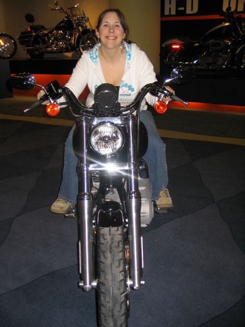 1993 Ford Taurus - A woman poses on a motorcycle at what appears to be a dealership or auto show.