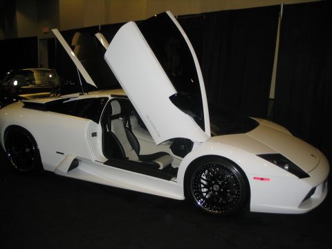 1993 Ford Taurus - A white sports car with its doors open is displayed indoors, with another vehicle partially visible in the background.