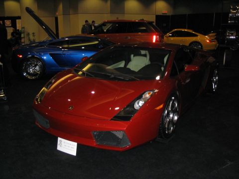 1993 Ford Taurus - A red sports car is displayed at an auto show, with other vehicles in the background.