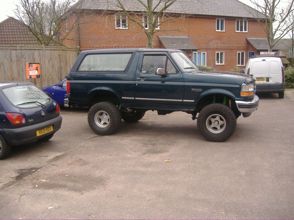 Lifted dark green two-door Ford Bronco SUV on big tires in a parking lot