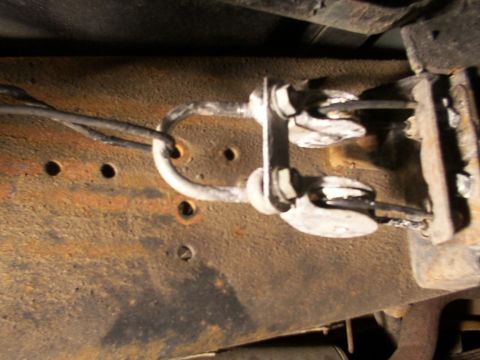 1995 Ford C-350 (Centurion Conversions) - Close-up of a vehicle's brake cable assembly, showing the connection points and rusty frame.