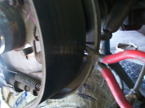 1995 Ford C-350 (Centurion Conversions) - A mechanic uses pliers to adjust a brake drum, likely for a truck or van.