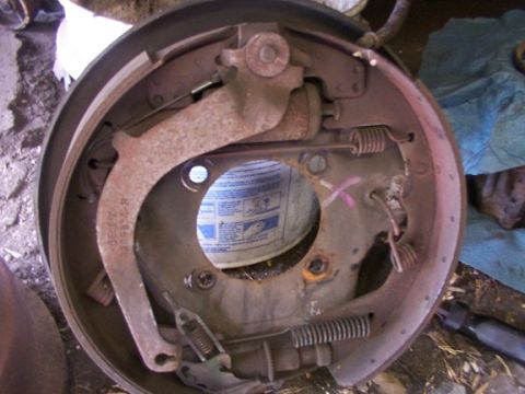 1995 Ford C-350 (Centurion Conversions) - Close-up of a rusty drum brake assembly, showing internal mechanical parts and springs.