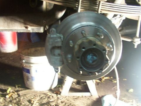 1995 Ford C-350 (Centurion Conversions) - Close-up of a vehicle's disc brake assembly, with buckets in the background.