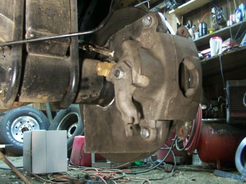 1995 Ford C-350 (Centurion Conversions) - Close-up view of a vehicle's rear brake caliper and rotor assembly, with workshop items in the background.