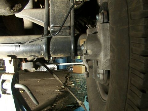 1995 Ford C-350 (Centurion Conversions) - Close-up view of a vehicle's rear axle and brake components, with a tire on the right side.
