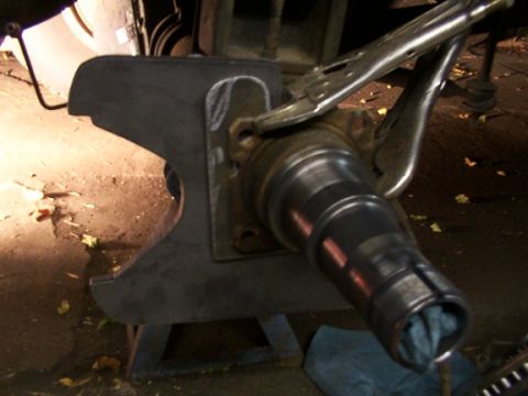 1995 Ford C-350 (Centurion Conversions) - Close-up of a vehicle's brake caliper bracket and spindle assembly, held by vise grips.