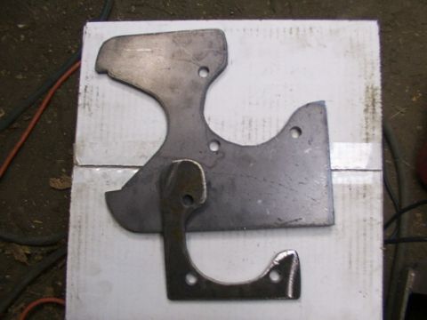 1995 Ford C-350 (Centurion Conversions) - Three metal brake caliper brackets are laid out on a white surface, likely for a vehicle repair or modification.