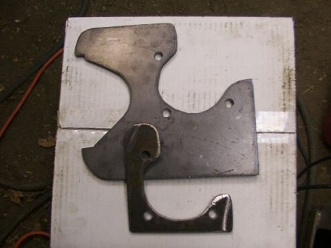 1995 Ford C-350 (Centurion Conversions) - Metal brake caliper brackets, possibly for a Ford C-350, are laid out on a white surface.