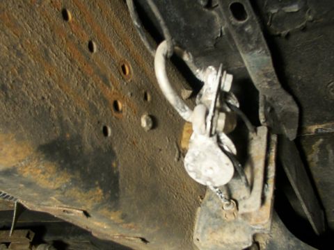 1995 Ford C-350 (Centurion Conversions) - Detail of a rusty underbody component, possibly related to a braking system.