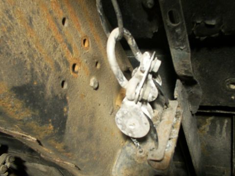 1995 Ford C-350 (Centurion Conversions) - Detail of a rusted metal bracket assembly with attached cables and fasteners.