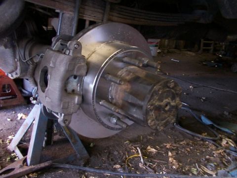 1995 Ford C-350 (Centurion Conversions) - Close-up view of a rear axle disc brake assembly, supported by jack stands.